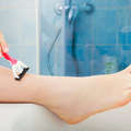 Icon woman shaving legs with razor in bathroom 508665640 1258x838