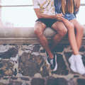 Icon legs of hipster couple sitting on a wall holding hands 469253724 1258x838